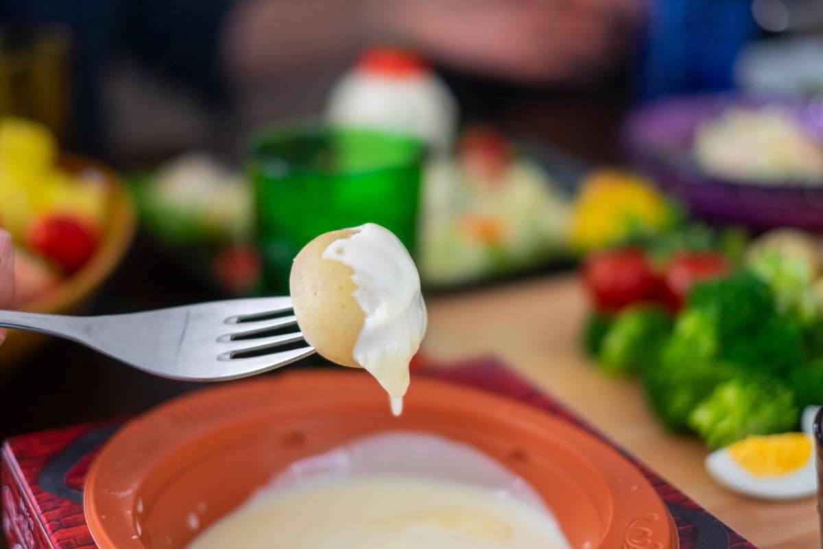 forchetta con patata lessa e contenitore con fonduta