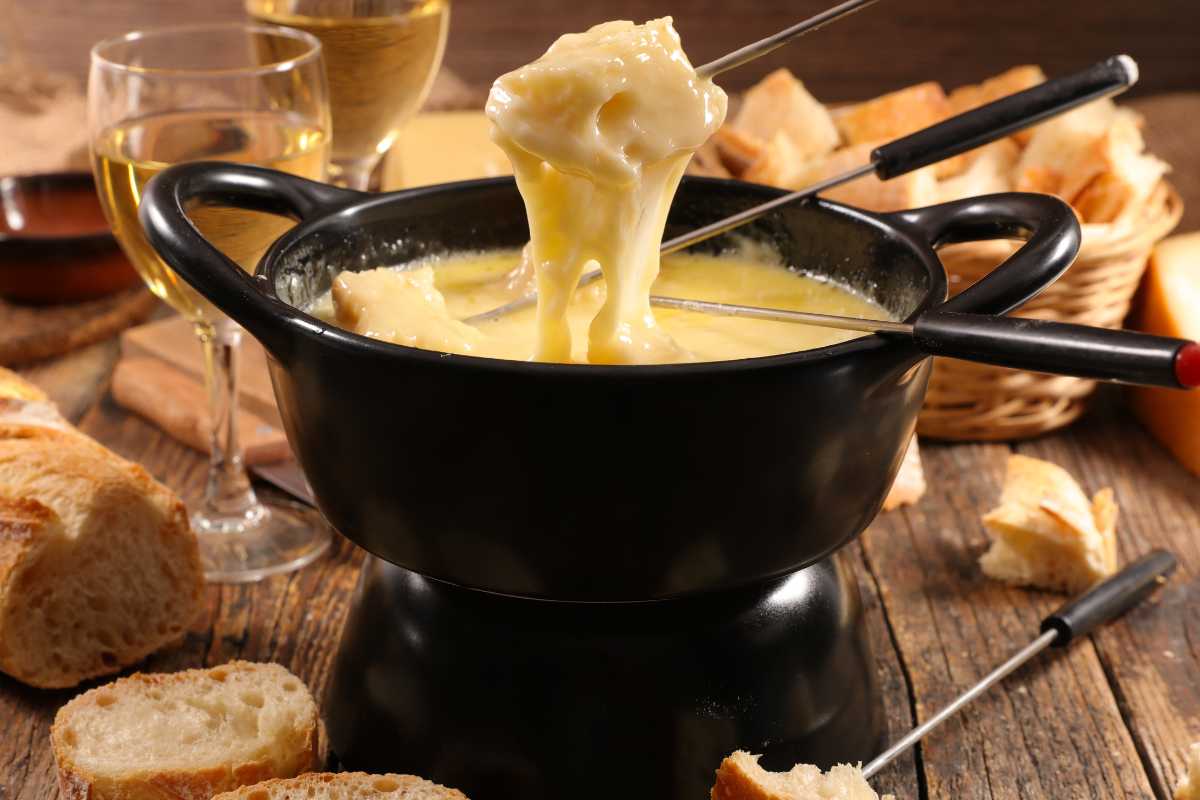 forchette che mangiano la fonduta dentro una pentola