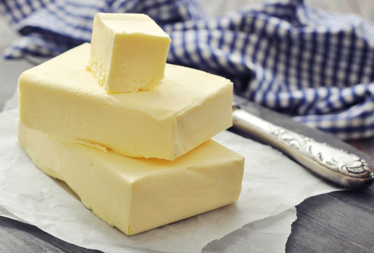 pezzi di burro appoggiati su carta con accanto coltello e strofinaccio da cucina 