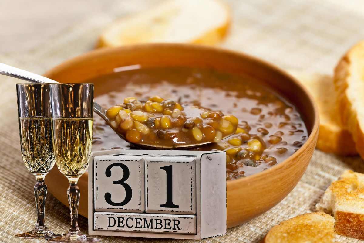 ciotola con lenticchie cotte e due calici di spumante accanto ad un calendario in legno che indica il 31 dicembre