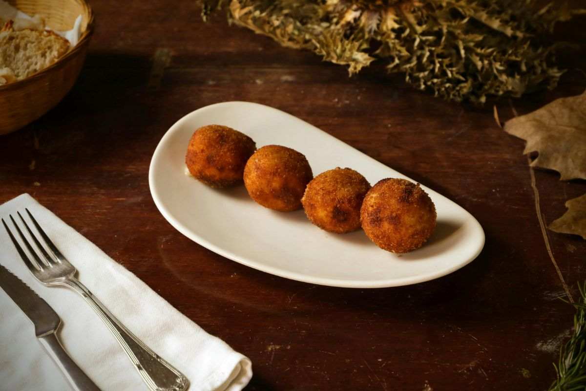 piccolo piatto di ceramica con 4 arancini posto su un tavolo apparecchiato
