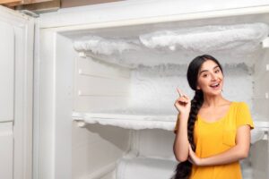 donna con mano alzata e congelatore aperto