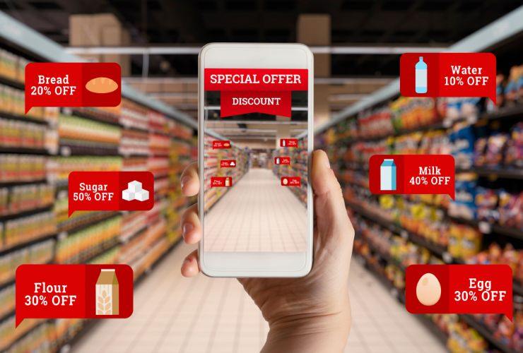 corsia di un supermercato, donna che tiene telefono in mano e cartellini di sconti