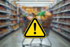 carrello della spesa pieno tra le corsie del supermercato e segnale di pericolo