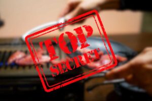 chef che prende carne dalla griglia e scritta top secret